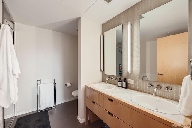 bathroom with double vanity, backsplash, a sink, and toilet