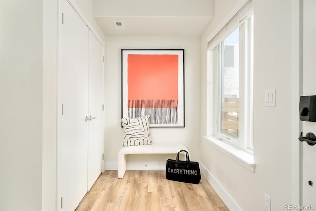 mudroom featuring baseboards, light wood finished floors, visible vents, and a healthy amount of sunlight