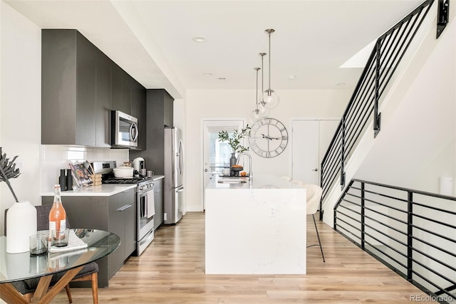 kitchen featuring stainless steel appliances, light countertops, light wood-style flooring, modern cabinets, and dark cabinets