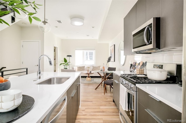 kitchen featuring stainless steel appliances, modern cabinets, a sink, and light wood-style flooring