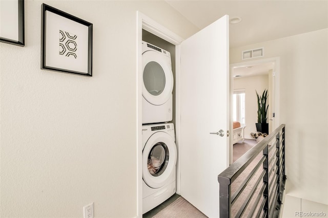 washroom with visible vents, laundry area, and stacked washer and clothes dryer