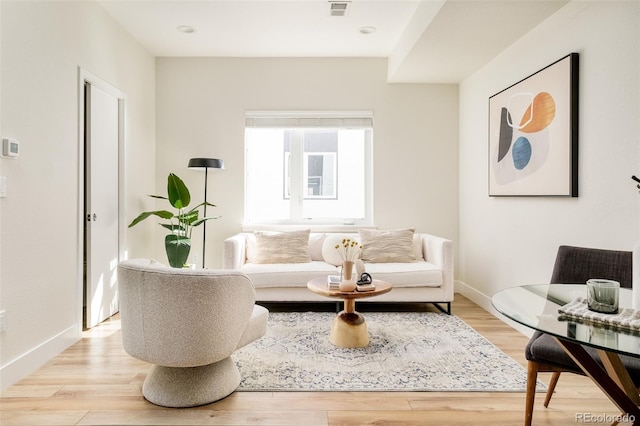 living room featuring light wood finished floors, visible vents, and baseboards