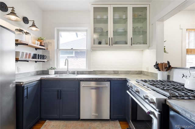 kitchen with light countertops, a sink, glass insert cabinets, and stainless steel appliances