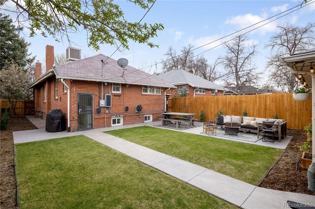 back of house with an outdoor living space with a fire pit, a patio, a fenced backyard, a chimney, and a yard