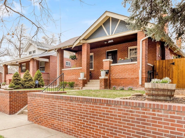 view of front facade with brick siding, fence, and a porch