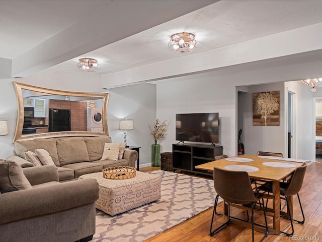 living room featuring hardwood / wood-style floors, a chandelier, and stacked washing maching and dryer