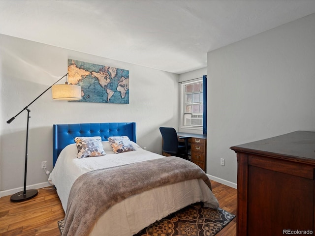 bedroom with cooling unit, built in desk, and hardwood / wood-style floors