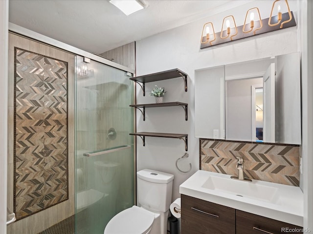 bathroom with tasteful backsplash, a stall shower, vanity, and toilet