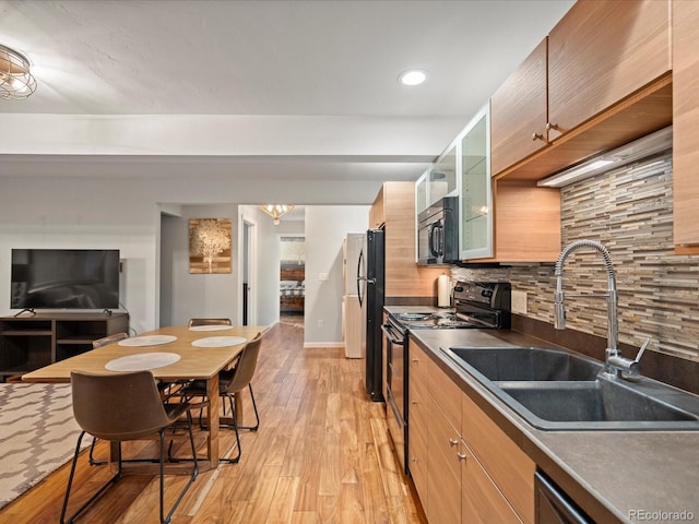 kitchen featuring electric range, decorative backsplash, dark countertops, glass insert cabinets, and a sink