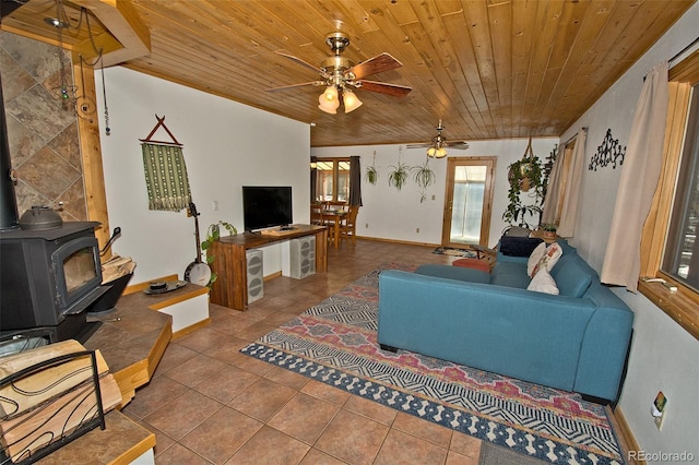 living room featuring tile patterned floors, ceiling fan, a wood stove, and wooden ceiling