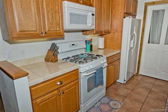 kitchen with tile counters, white appliances, and light tile patterned floors