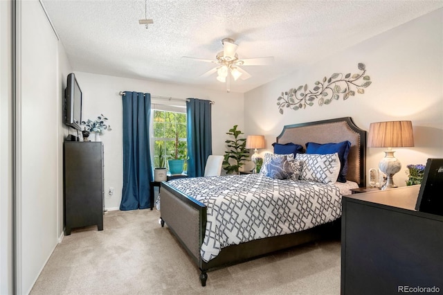 bedroom with a ceiling fan, light colored carpet, and a textured ceiling