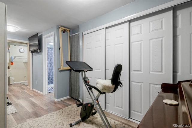 workout area featuring light wood-style flooring and baseboards