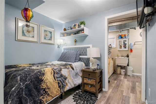 bedroom with baseboards, wood finished floors, and ensuite bathroom