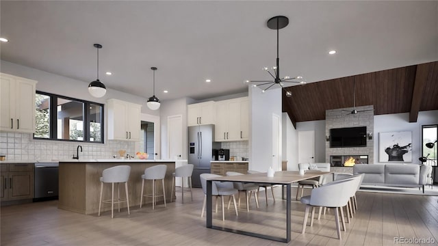 kitchen with decorative backsplash, a kitchen island, white cabinetry, a fireplace, and appliances with stainless steel finishes