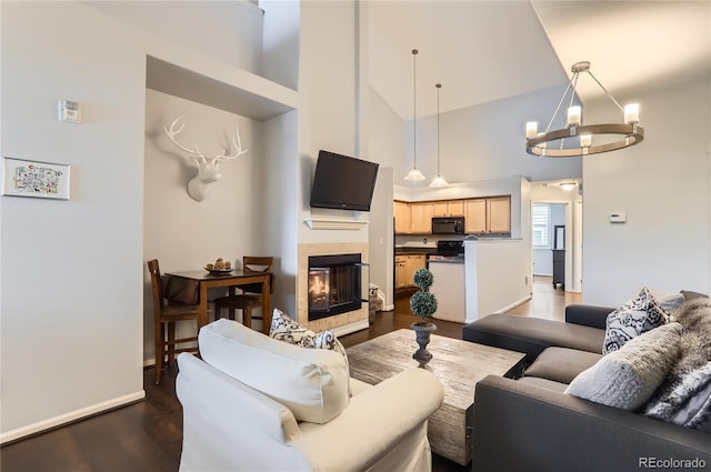 living area with a chandelier, high vaulted ceiling, dark wood-type flooring, a fireplace, and baseboards