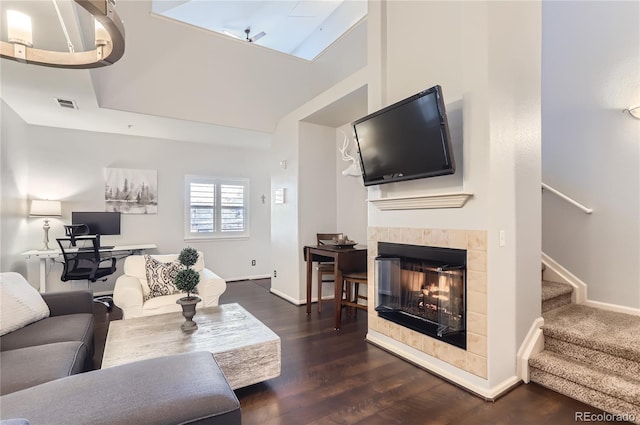 living area with a fireplace, visible vents, stairway, dark wood-type flooring, and baseboards