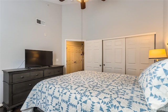 bedroom with a closet, visible vents, a ceiling fan, and a high ceiling