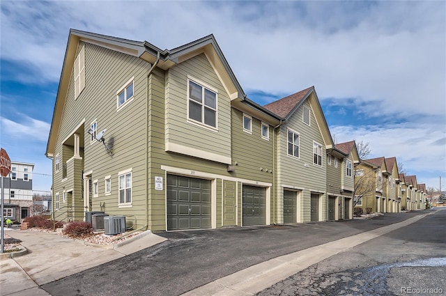 view of property exterior with a garage, cooling unit, and a residential view