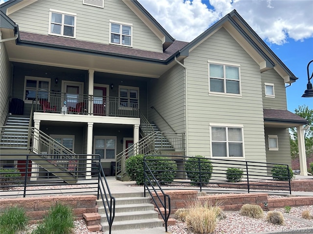 view of front of property featuring a porch, stairway, and roof with shingles
