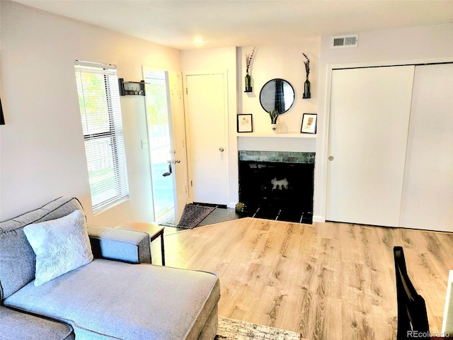 living room with wood-type flooring and a tiled fireplace