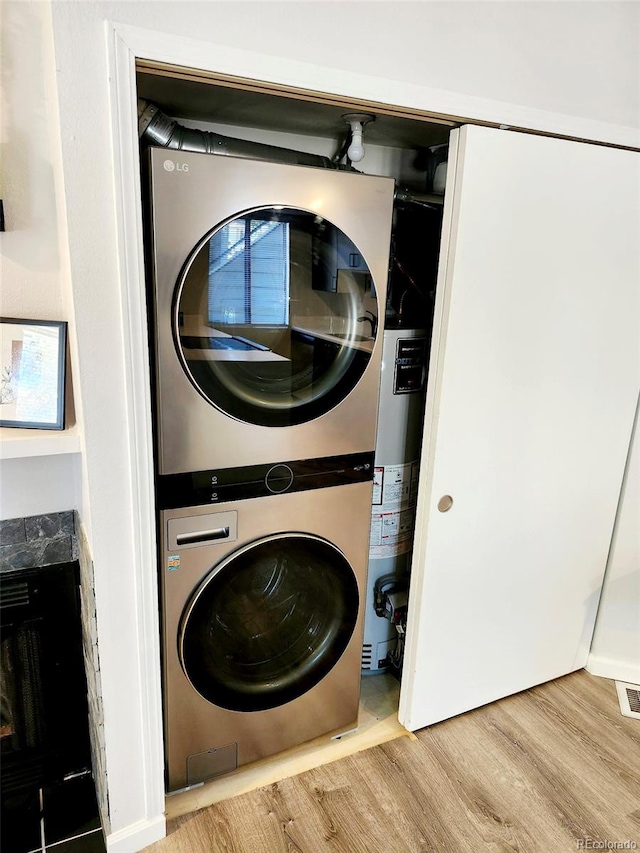 laundry room with stacked washer and clothes dryer and light hardwood / wood-style floors