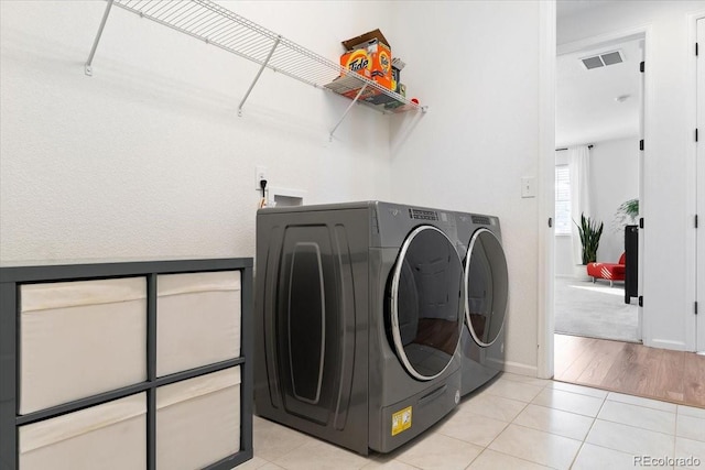 laundry room with washer and dryer and light tile patterned floors