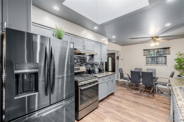 9170 Aspen Dr, Thornton, CO 80229 - kitchen with appliances with stainless steel finishes, under cabinet range hood, backsplash, light wood-type flooring, and a ceiling fan