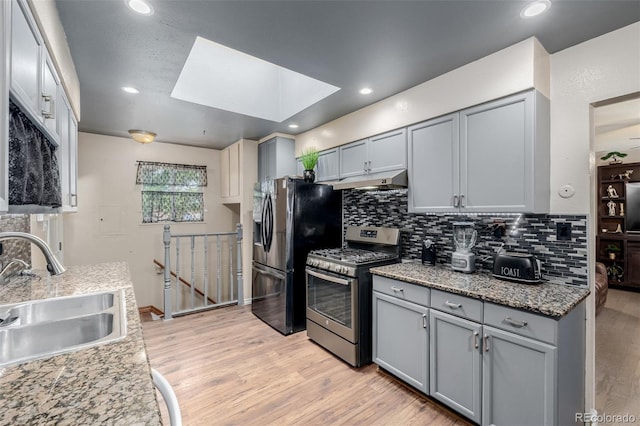 9170 Aspen Dr, Thornton, CO 80229 - kitchen with stainless steel range with gas cooktop, gray cabinetry, a skylight, refrigerator with ice dispenser, and tasteful backsplash