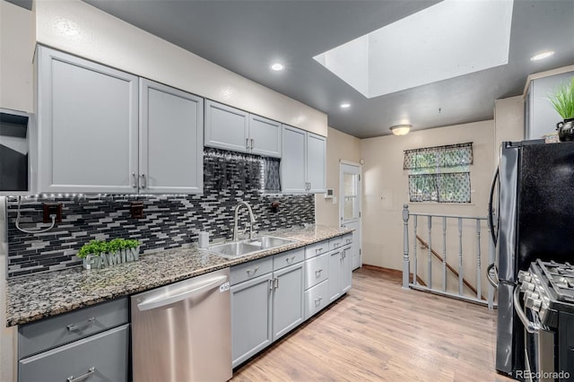 9170 Aspen Dr, Thornton, CO 80229 - kitchen with stainless steel appliances, gray cabinetry, tasteful backsplash, light wood finished floors, and a skylight