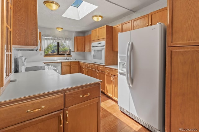 1400 S Knox Ct, Denver, CO 80219 - kitchen with white appliances, a skylight, a sink, light wood-style flooring, and light countertops