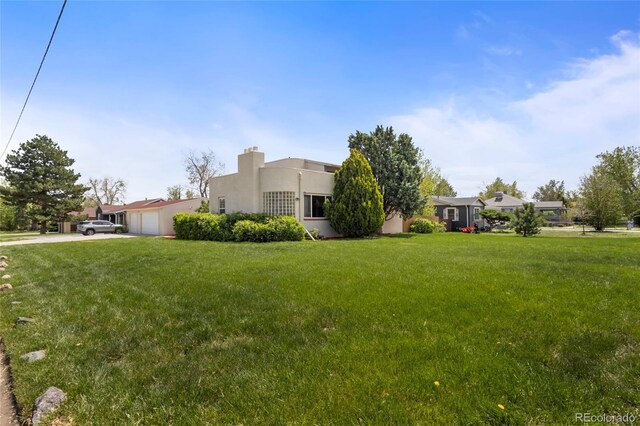 1400 S Knox Ct, Denver, CO 80219 - view of front of house featuring a garage, a front yard, stucco siding, and concrete driveway