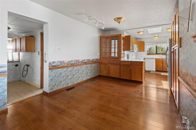 1400 S Knox Ct, Denver, CO 80219 - kitchen featuring white appliances, wallpapered walls, dark wood finished floors, brown cabinets, and glass insert cabinets
