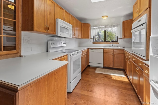1400 S Knox Ct, Denver, CO 80219 - kitchen featuring white appliances, light wood-type flooring, backsplash, a sink, and brown cabinetry