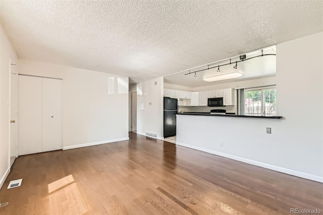 5556 Vaughn St, Denver, CO 80239 - unfurnished living room with wood finished floors, a textured ceiling, and rail lighting