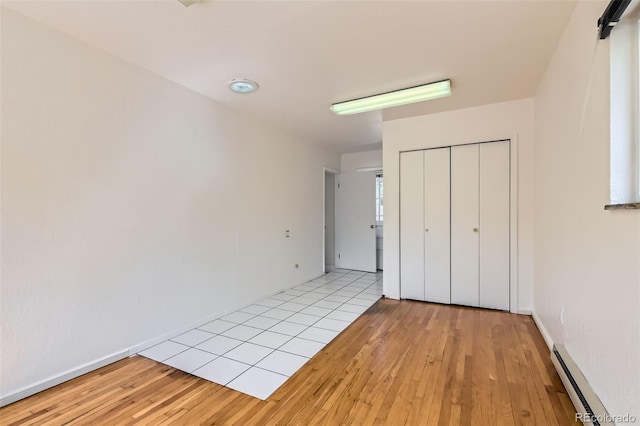 5556 Vaughn St, Denver, CO 80239 - unfurnished bedroom with baseboard heating, wood-type flooring, and a closet