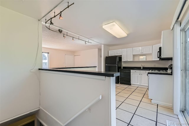 5556 Vaughn St, Denver, CO 80239 - kitchen featuring black appliances, dark countertops, white cabinets, light tile patterned floors, and a peninsula