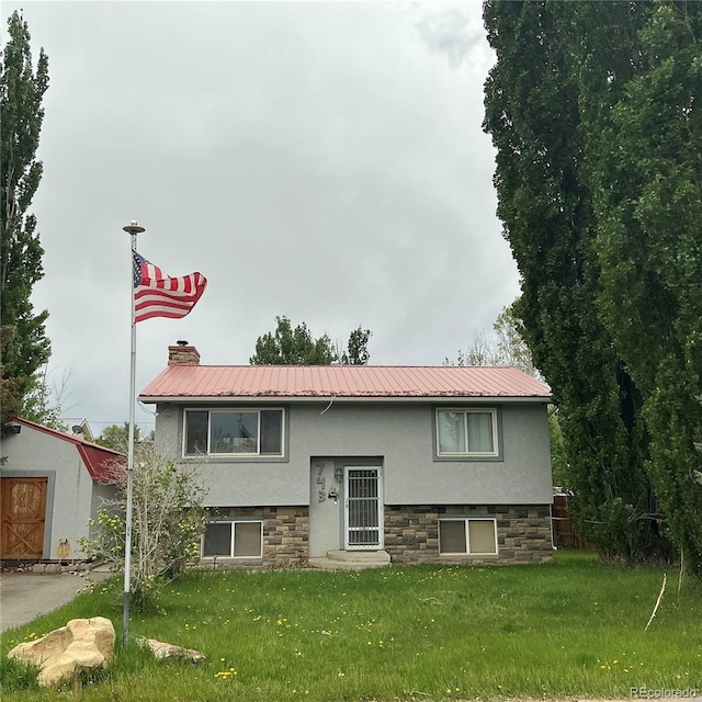 743 E Rangely Ave, Rangely, CO 81648 - view of front of house featuring a front yard, stucco siding, and metal roof