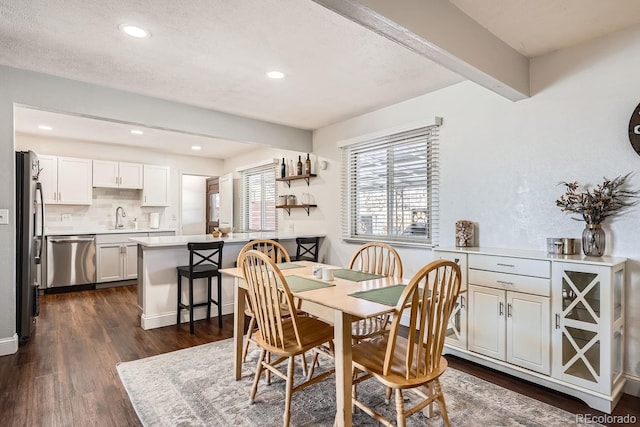 dining room with beam ceiling, dark hardwood / wood-style flooring, a textured ceiling, and sink