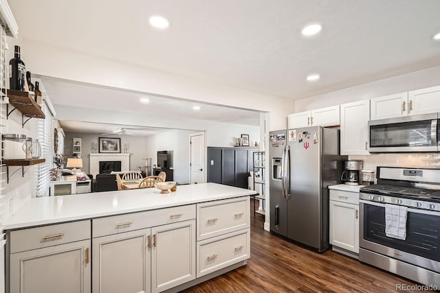 kitchen featuring white cabinetry, ceiling fan, a brick fireplace, dark hardwood / wood-style flooring, and appliances with stainless steel finishes