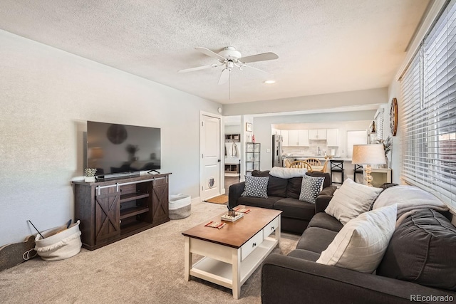 living room with ceiling fan, carpet floors, and a textured ceiling