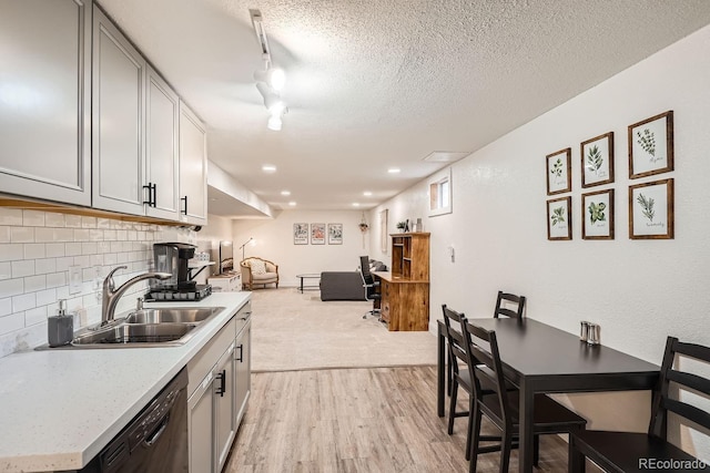 kitchen with sink, black dishwasher, tasteful backsplash, a textured ceiling, and track lighting