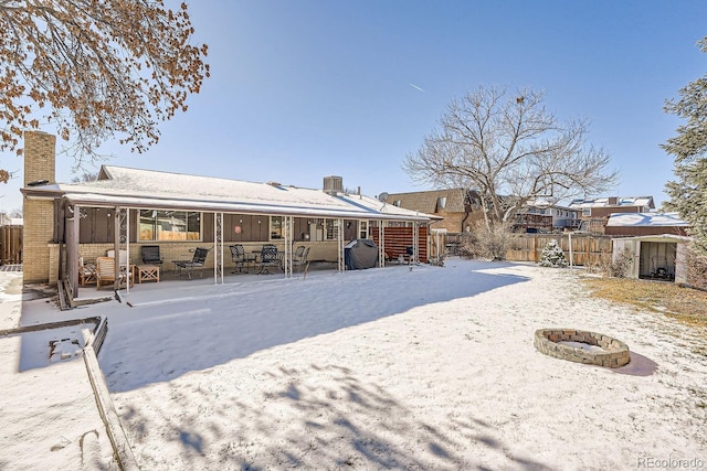 rear view of property featuring a fire pit