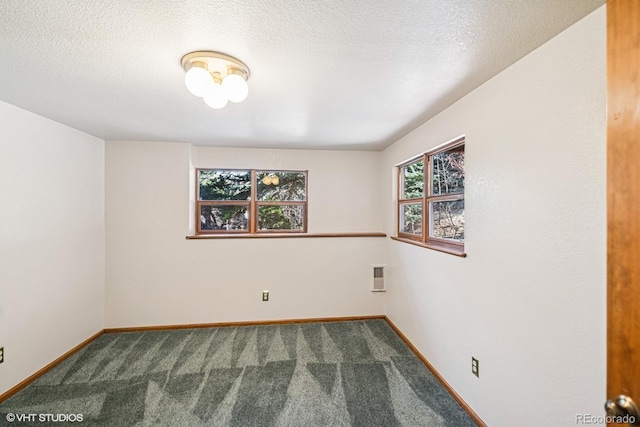 empty room with carpet flooring, a textured ceiling, and baseboards