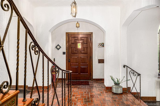 1795 N Monaco St Parkway, Denver, CO 80224 - foyer entrance with a textured wall, arched walkways, stairs, brick floors, and baseboards