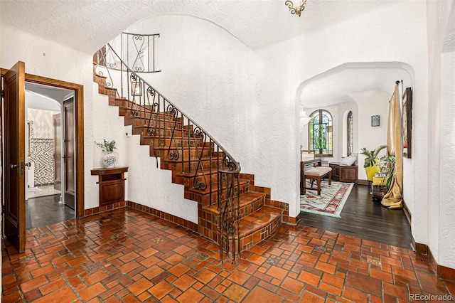 1795 N Monaco St Parkway, Denver, CO 80224 - stairs featuring arched walkways, a textured wall, and baseboards
