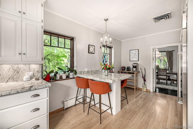 1795 N Monaco St Parkway, Denver, CO 80224 - kitchen with healthy amount of natural light, white cabinetry, a chandelier, and light wood-style floors