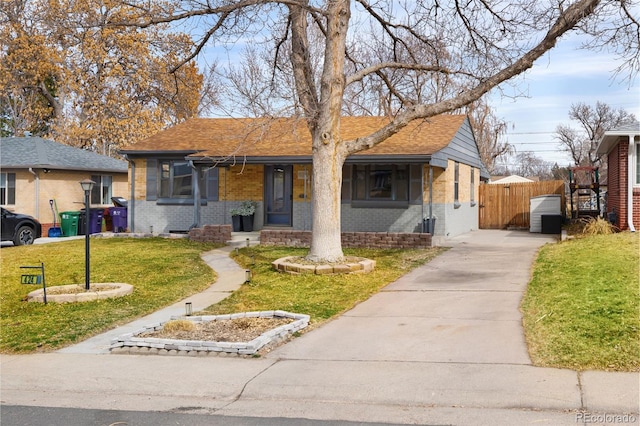 view of front facade featuring driveway, a front lawn, fence, a shingled roof, and brick siding