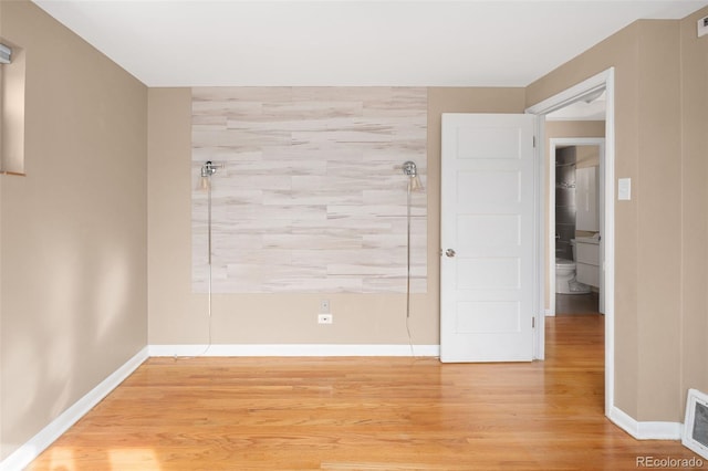 spare room featuring light wood-type flooring and baseboards