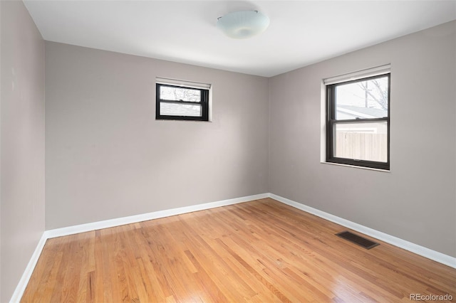 empty room with visible vents, light wood-style flooring, a healthy amount of sunlight, and baseboards